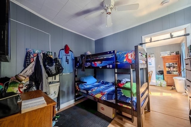 bedroom with wood finished floors, ceiling fan, and crown molding