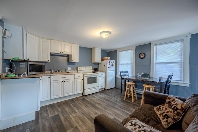 kitchen featuring white appliances, a sink, dark wood-style flooring, and white cabinetry