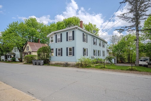 view of front of home with a chimney and fence