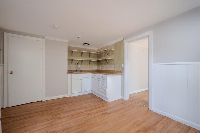 kitchen with open shelves, light wood-type flooring, a sink, white cabinets, and light countertops