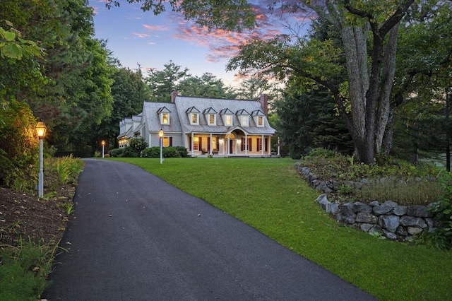 view of front of house with a chimney, aphalt driveway, and a yard