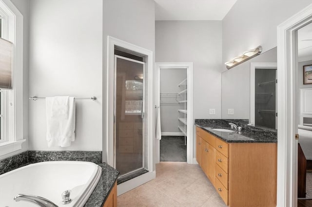 full bathroom featuring a stall shower, tile patterned floors, a garden tub, a spacious closet, and vanity