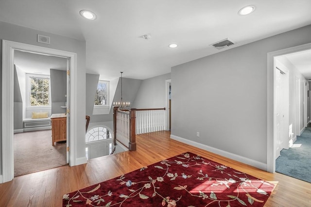 hall featuring visible vents, an upstairs landing, and wood finished floors