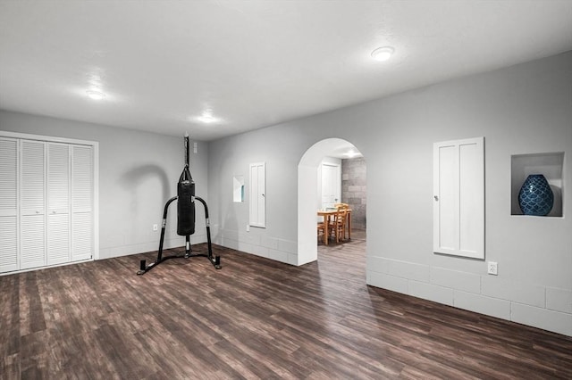 workout room with arched walkways and wood finished floors