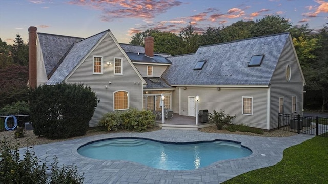 rear view of house with a fenced in pool, a chimney, central AC unit, a patio area, and a wooden deck