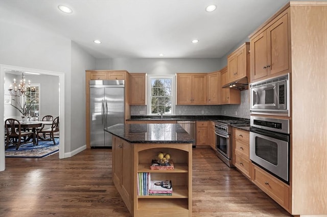 kitchen with dark wood-style floors, a kitchen island, built in appliances, under cabinet range hood, and backsplash