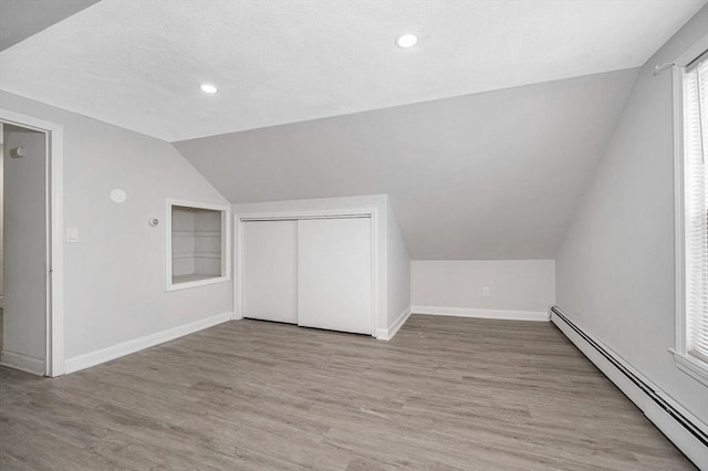 additional living space featuring light hardwood / wood-style flooring, a baseboard radiator, and lofted ceiling