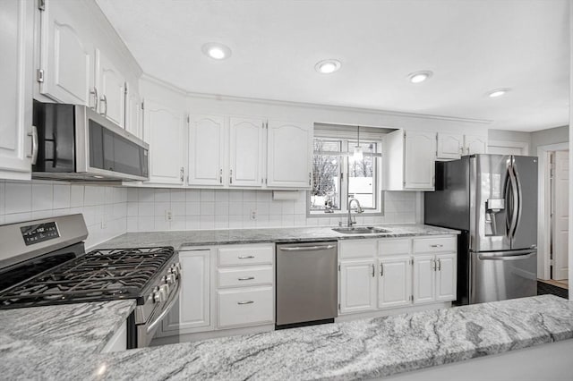 kitchen featuring sink, white cabinetry, stainless steel appliances, light stone countertops, and decorative backsplash