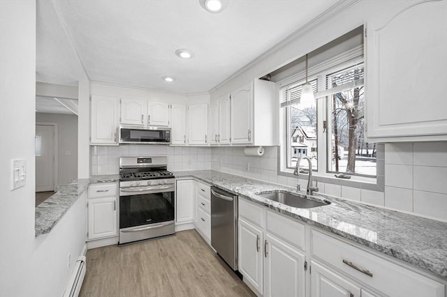 kitchen with appliances with stainless steel finishes, tasteful backsplash, white cabinetry, sink, and light hardwood / wood-style flooring