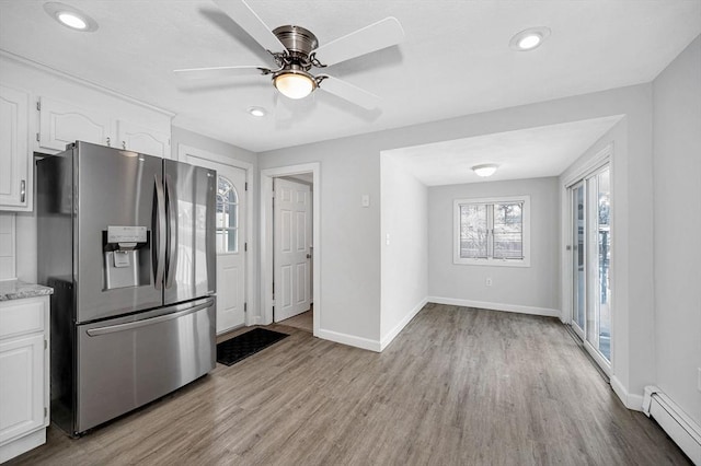 kitchen with stainless steel refrigerator with ice dispenser, a baseboard radiator, white cabinetry, and light hardwood / wood-style flooring