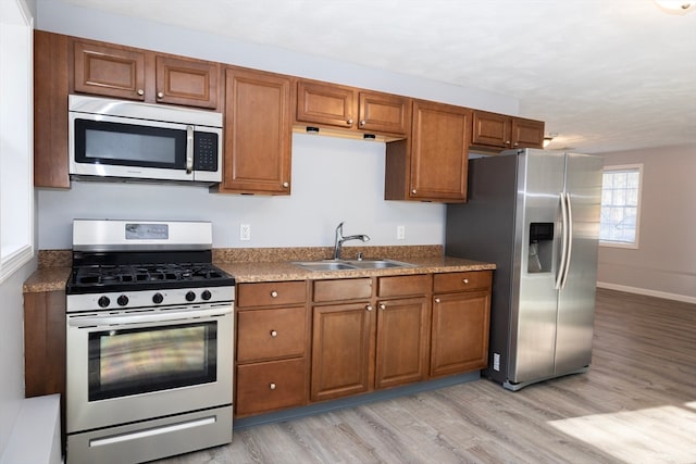 kitchen with sink, stainless steel appliances, and light wood-type flooring