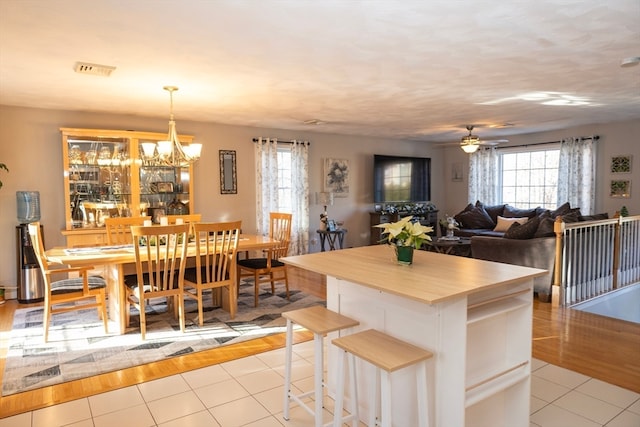 kitchen featuring a kitchen bar, light wood-type flooring, decorative light fixtures, and ceiling fan with notable chandelier