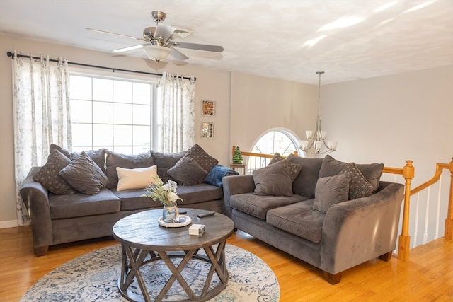 living room featuring ceiling fan with notable chandelier and light hardwood / wood-style floors