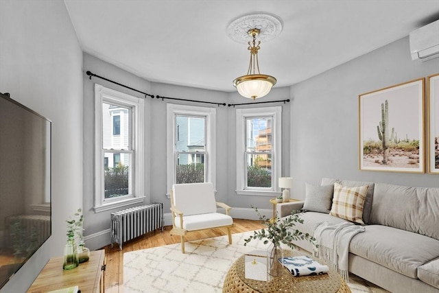 living room featuring baseboards, a wall mounted AC, radiator heating unit, and wood finished floors