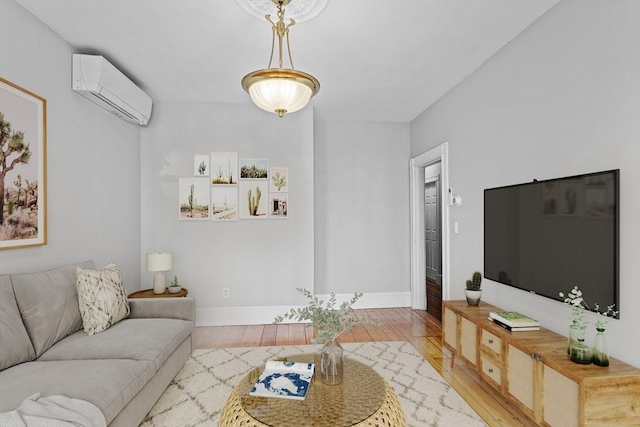 living area with baseboards, an AC wall unit, and wood finished floors