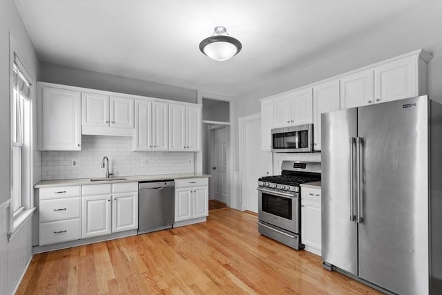 kitchen with light countertops, white cabinetry, tasteful backsplash, a sink, and stainless steel appliances