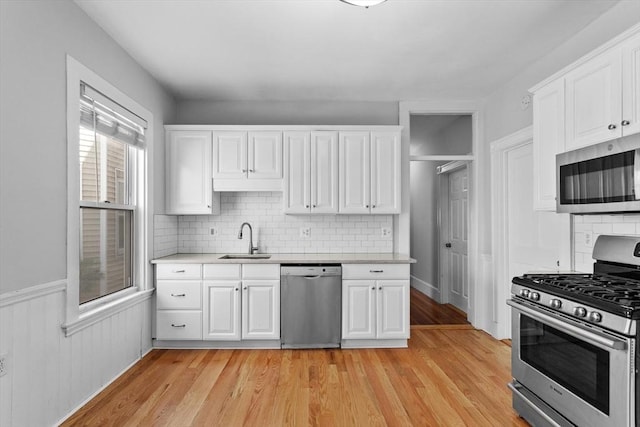 kitchen with a sink, appliances with stainless steel finishes, white cabinets, and decorative backsplash