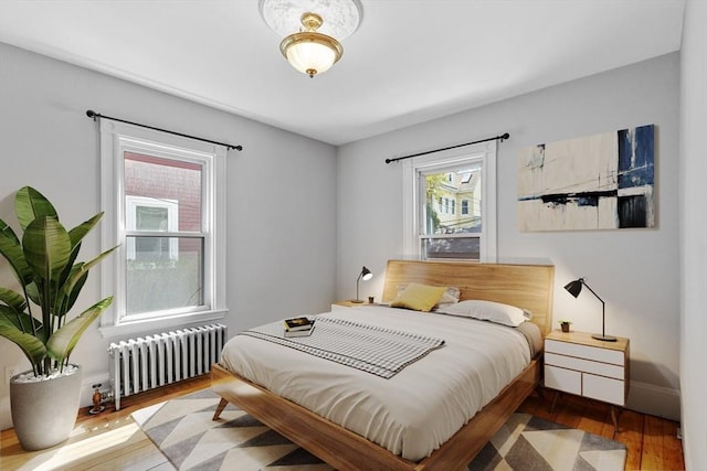 bedroom featuring wood finished floors, baseboards, and radiator heating unit
