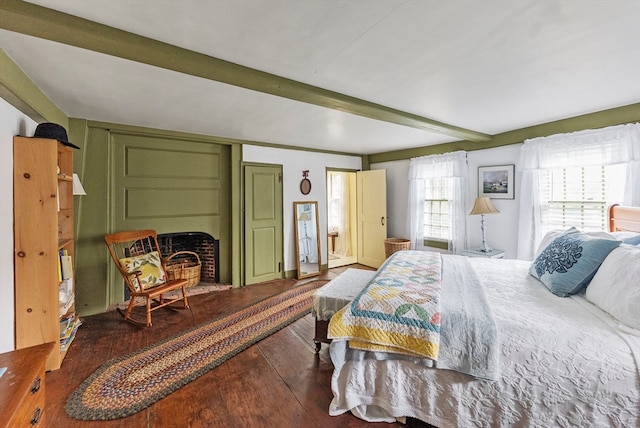 bedroom featuring beam ceiling, hardwood / wood-style flooring, and a fireplace