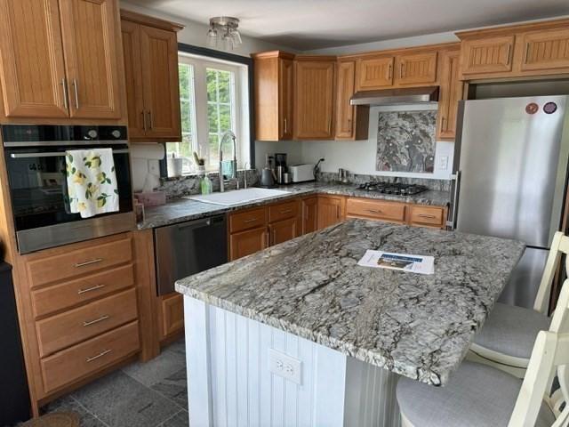 kitchen featuring a breakfast bar, a center island, sink, and stainless steel appliances