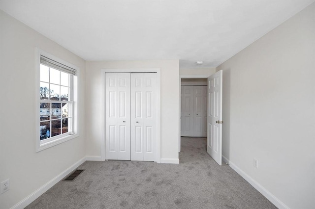 unfurnished bedroom featuring light colored carpet and a closet