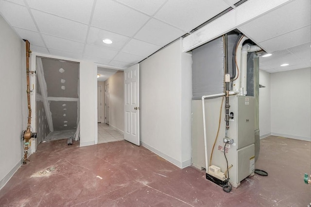 basement featuring a paneled ceiling and heating unit