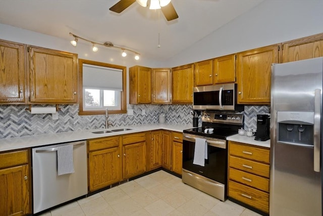 kitchen with ceiling fan, lofted ceiling, brown cabinetry, stainless steel appliances, and a sink