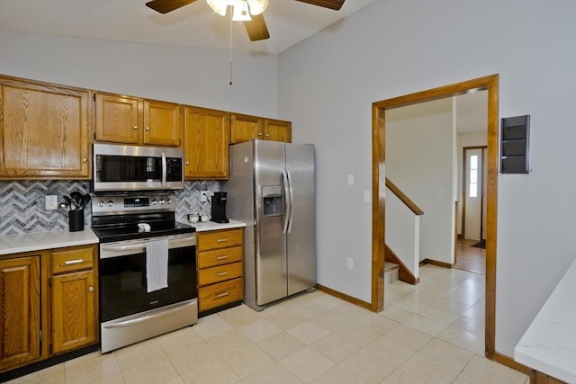 kitchen featuring brown cabinets, a ceiling fan, appliances with stainless steel finishes, light countertops, and lofted ceiling