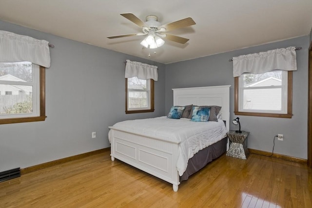 bedroom featuring baseboards, light wood finished floors, and ceiling fan