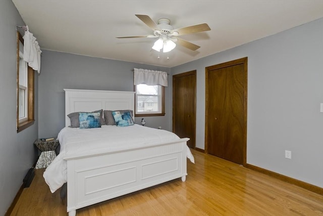 bedroom with light wood finished floors, baseboards, and multiple closets