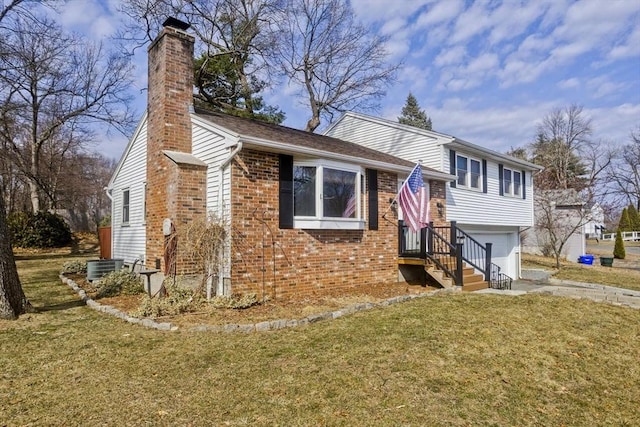 split level home featuring brick siding, a front lawn, a chimney, driveway, and an attached garage