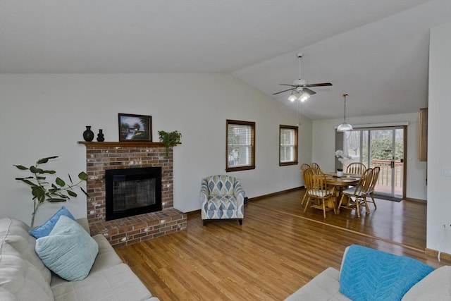 living area with lofted ceiling, a ceiling fan, wood finished floors, a fireplace, and baseboards