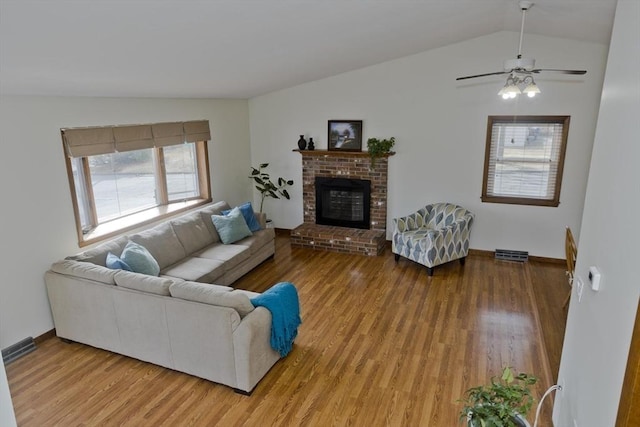 living room featuring light wood-type flooring, baseboards, a brick fireplace, ceiling fan, and vaulted ceiling