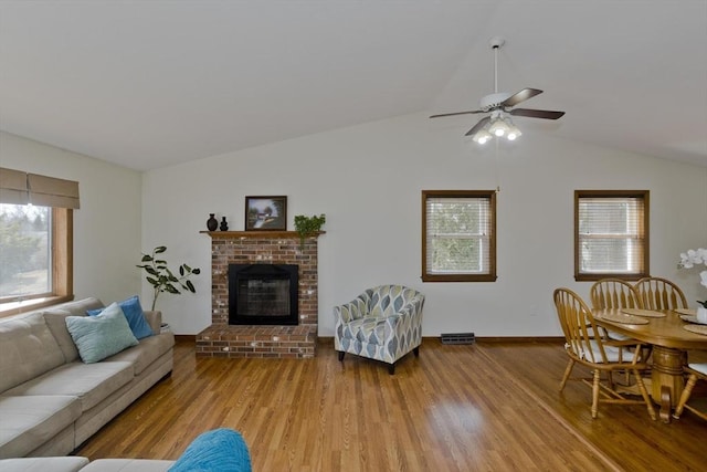 living area with plenty of natural light, lofted ceiling, a ceiling fan, and wood finished floors