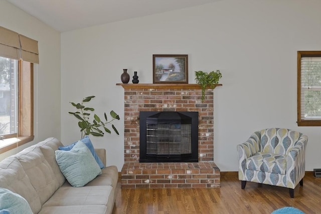 living area featuring a brick fireplace and wood finished floors