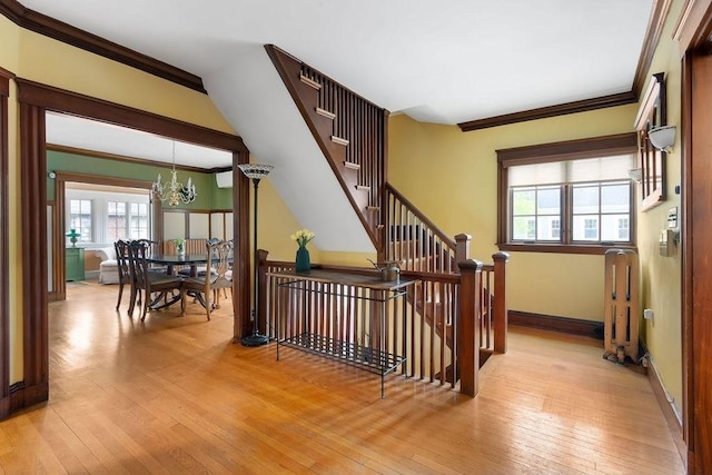 staircase with a chandelier, ornamental molding, hardwood / wood-style flooring, and baseboards