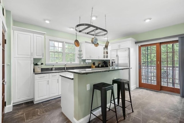 kitchen featuring dark marble finish flooring, white cabinetry, a kitchen bar, a sink, and recessed lighting