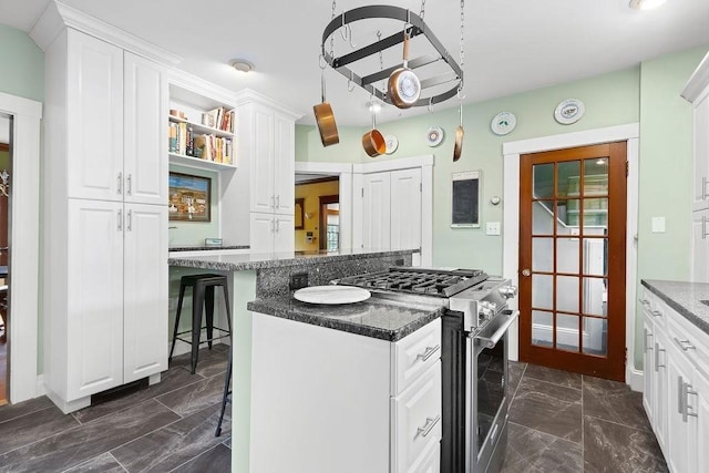 kitchen featuring high end stainless steel range oven, a kitchen breakfast bar, white cabinets, a center island, and dark marble finish flooring