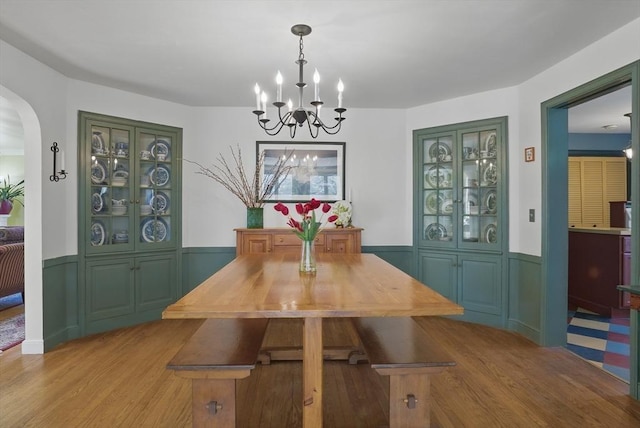 128 Lovell Rd, Holden, MA 01520 - dining space with a chandelier, arched walkways, wood finished floors, wainscoting, and a decorative wall