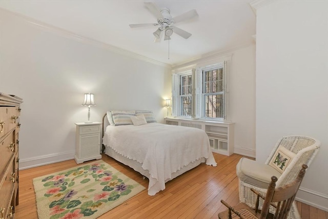 bedroom featuring light wood finished floors, crown molding, baseboards, and ceiling fan