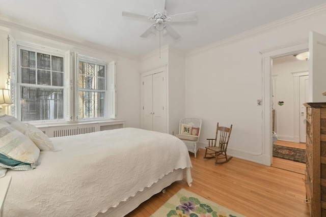 bedroom featuring light wood-type flooring, crown molding, a closet, ceiling fan, and baseboards