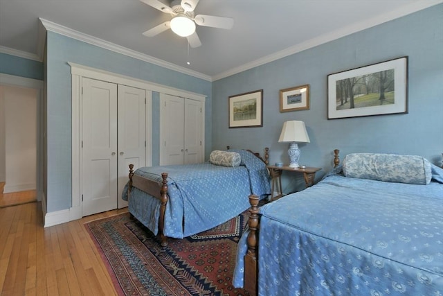 bedroom featuring multiple closets, light wood-style floors, baseboards, crown molding, and ceiling fan