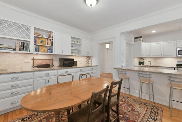 dining area with ornamental molding and light wood-style floors