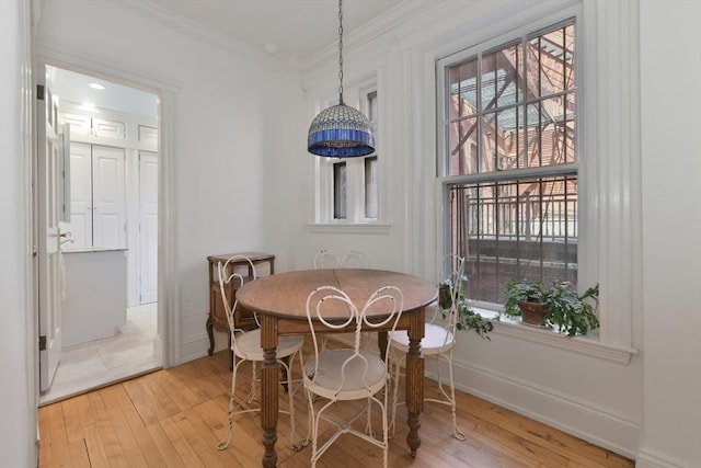 dining area with light wood-style flooring, crown molding, and baseboards