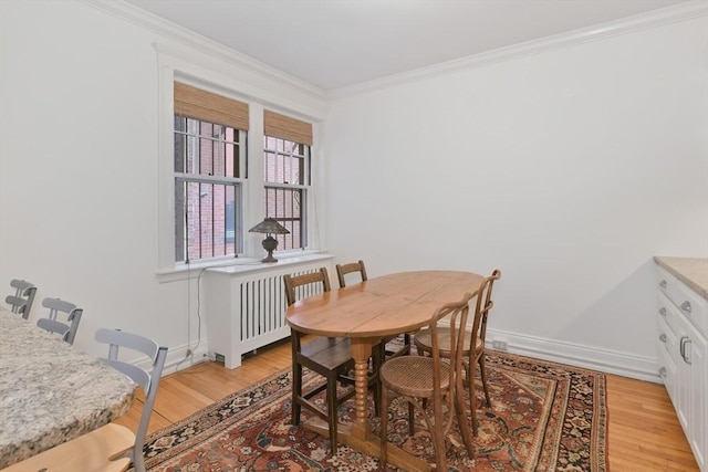 dining area with light wood-style flooring, crown molding, radiator heating unit, and baseboards