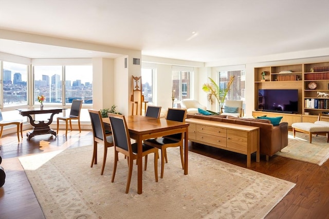 dining space featuring wood finished floors, visible vents, and a city view