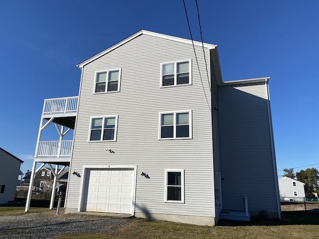 rear view of property with a garage and a balcony