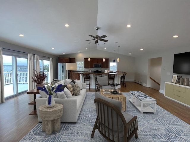 living room with ceiling fan, hardwood / wood-style floors, and vaulted ceiling