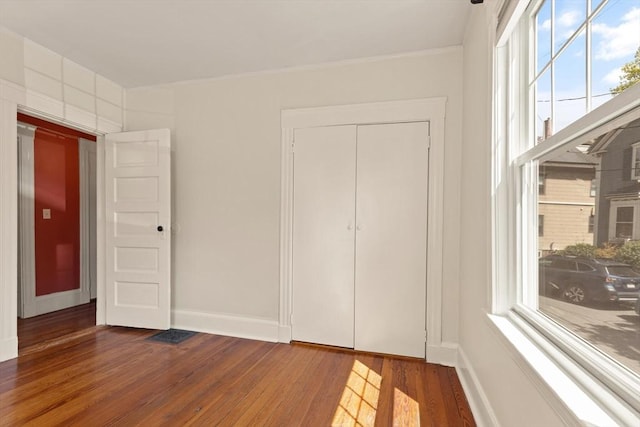 unfurnished bedroom with wood-type flooring, baseboards, and ornamental molding