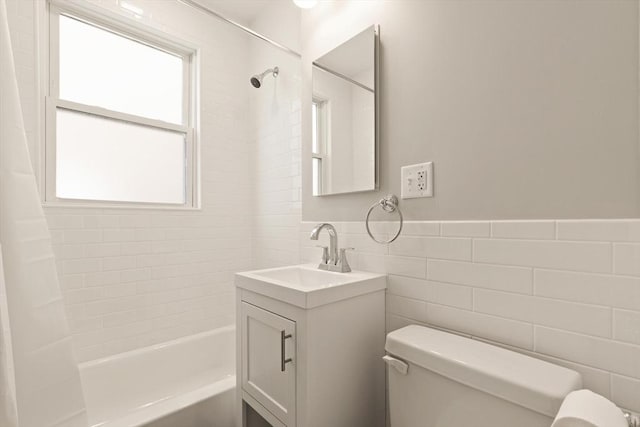 bathroom featuring tile walls, toilet, shower / bath combo, vanity, and wainscoting